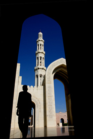Man in shadow with sunlit mosque in the background.